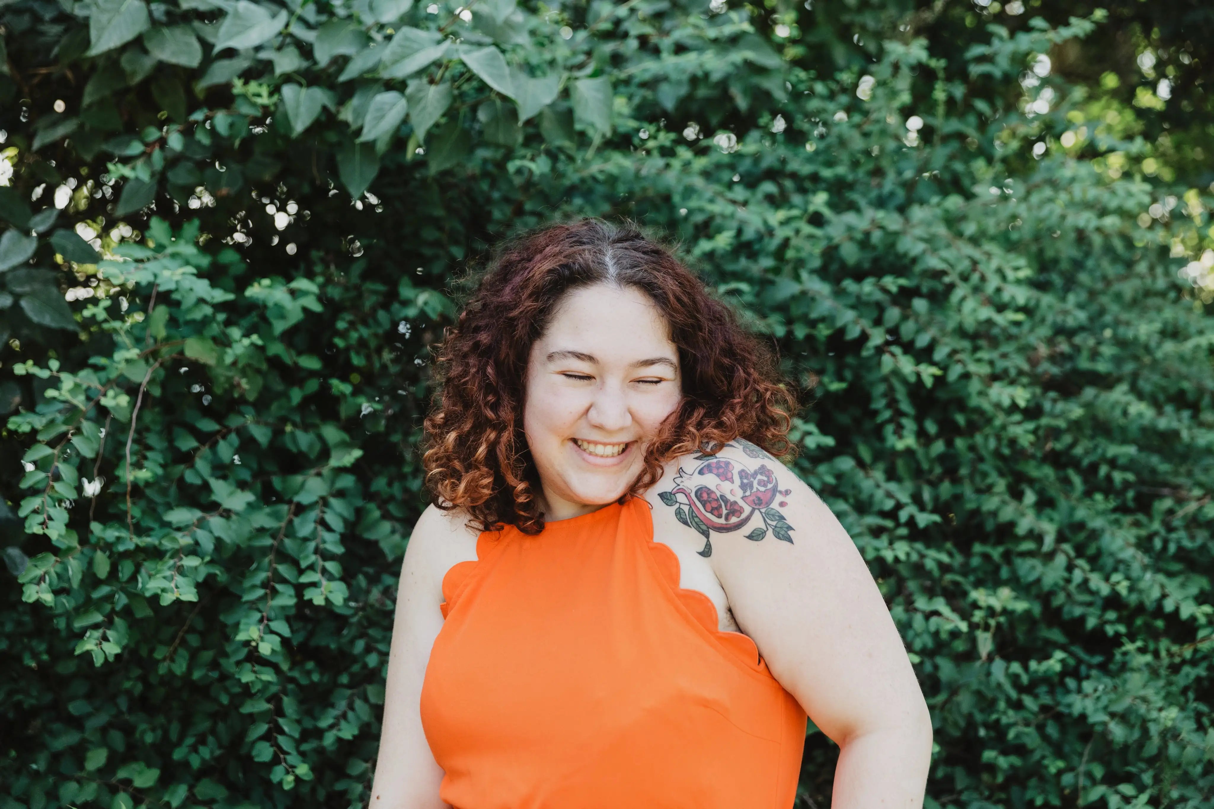 files/young-woman-in-orange-shirt-with-pomegranate-tattoo.webp